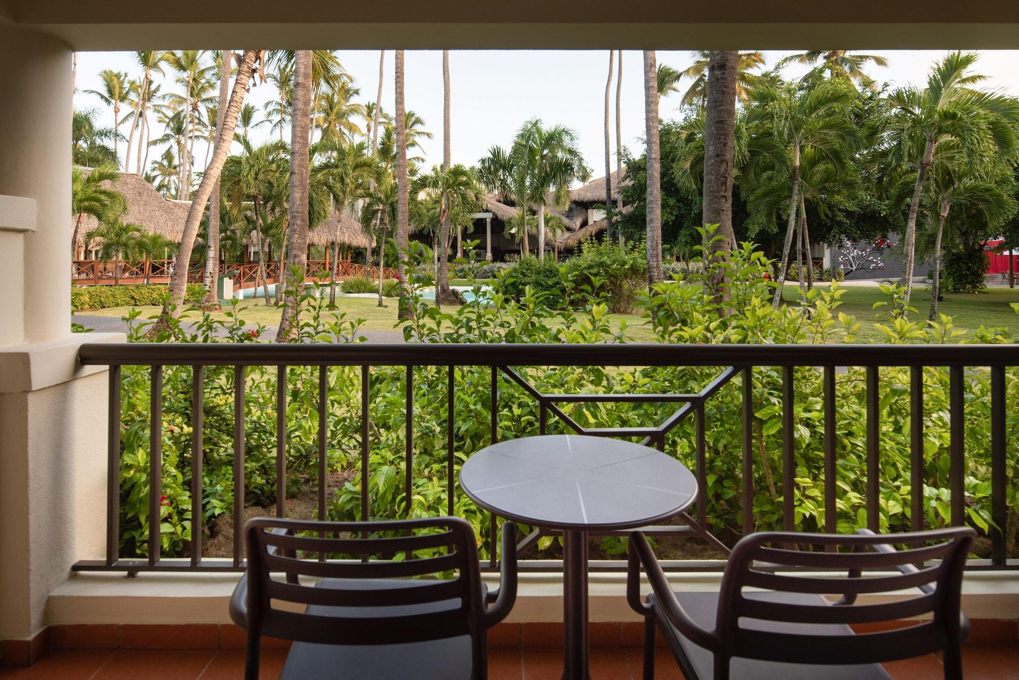 Impressive Punta Cana Esterno foto The photo shows a view from a balcony with two black chairs and a small round table. In the background, there is a lush green landscape filled with palm trees and other vegetation, suggesting a tropical setting. The area appears well-maintained, with