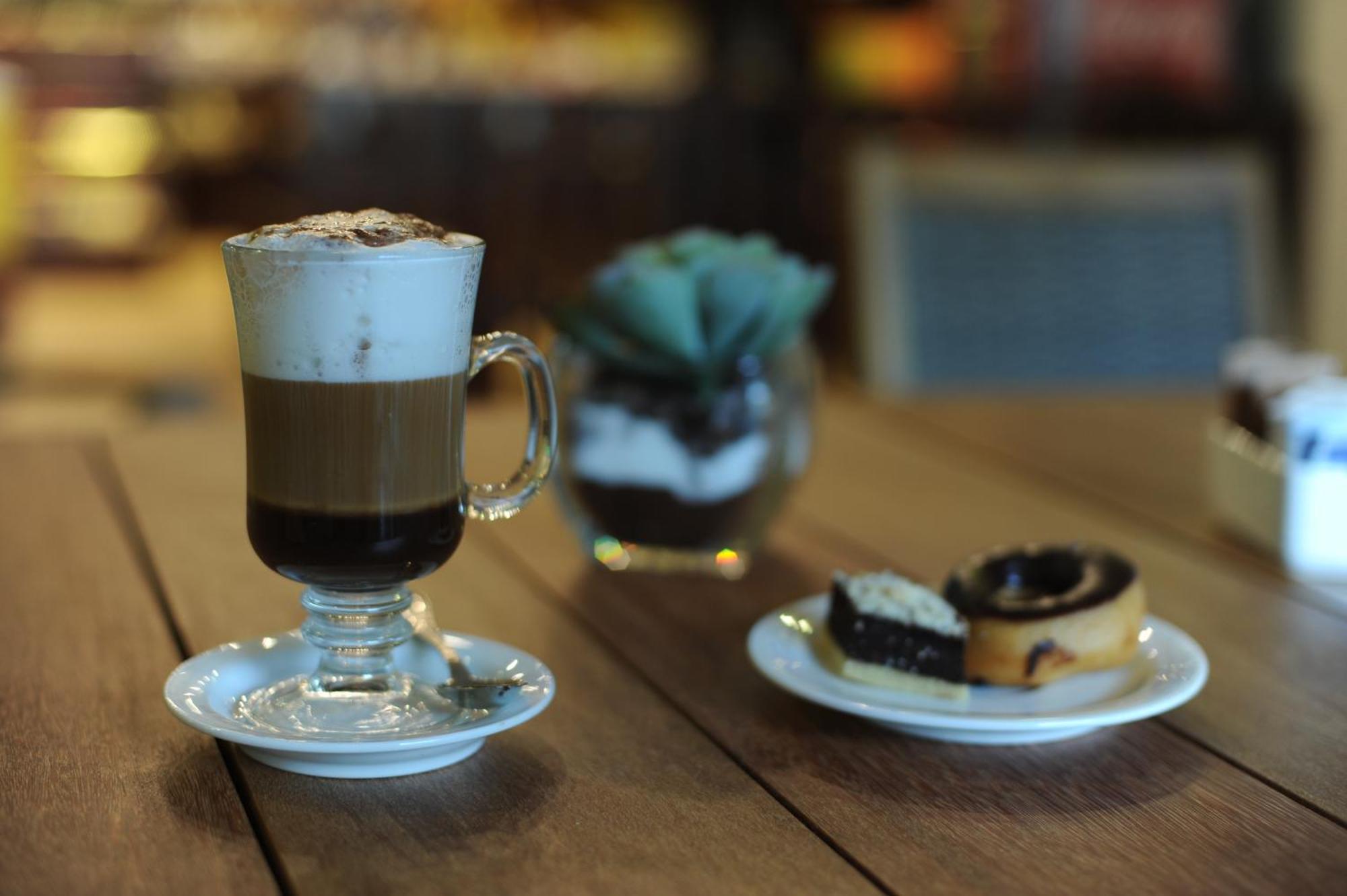 Impressive Punta Cana Esterno foto The photo shows a glass of layered coffee topped with foam and possibly cocoa powder, presented on a small white plate. Beside the coffee, there is a plate with two types of pastries: one appears to be a swirl-shaped pastry, likely cinnamon or chocol